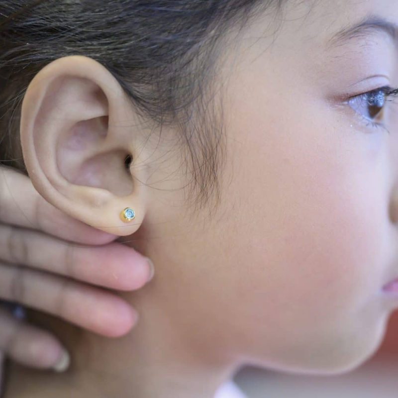 Adorable Little Asian Girl Having Ear Piercing Process.